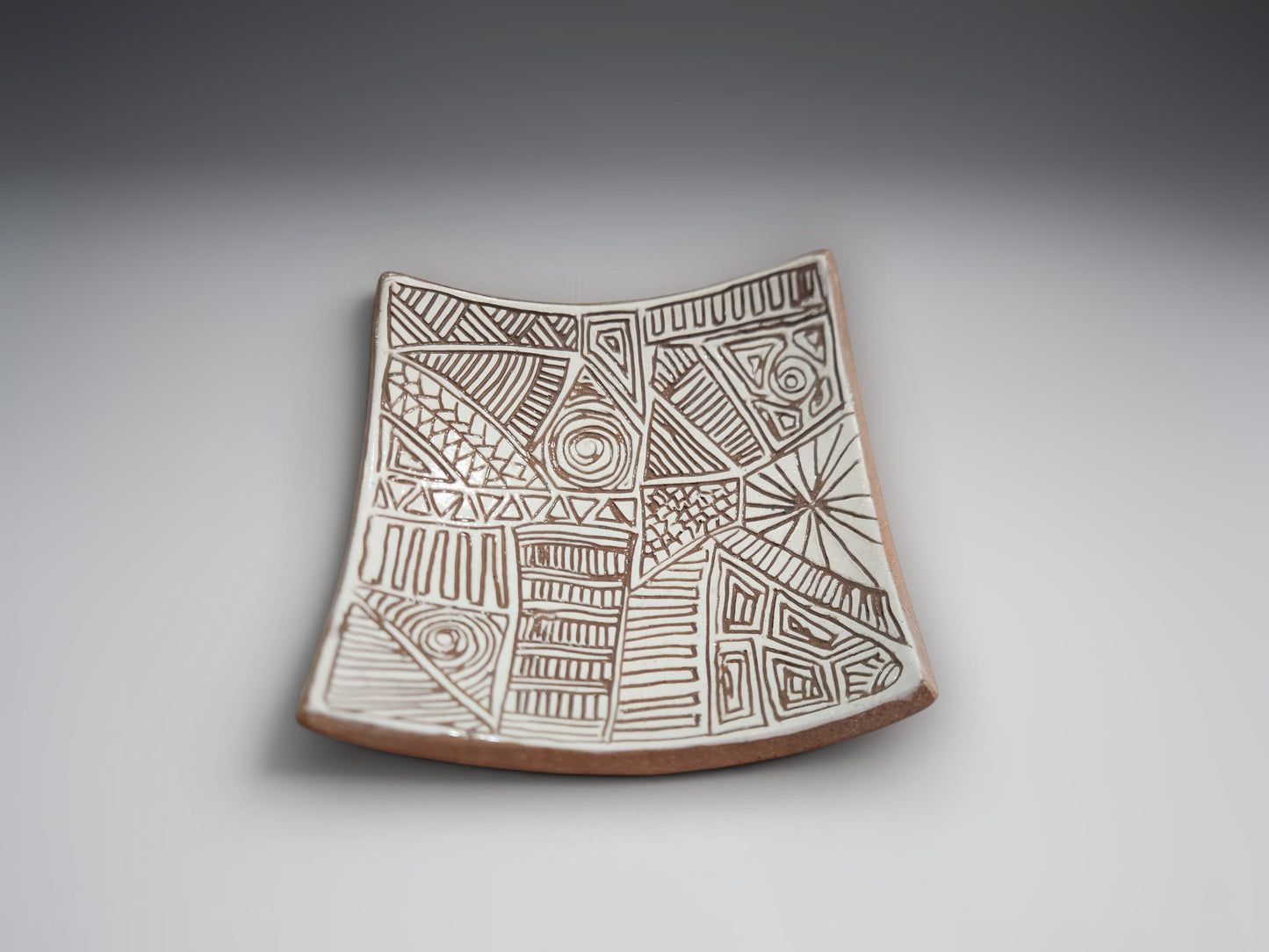 Artisan ceramic bowl-plate featuring intricate hand-carved patterns in natural terracotta clay