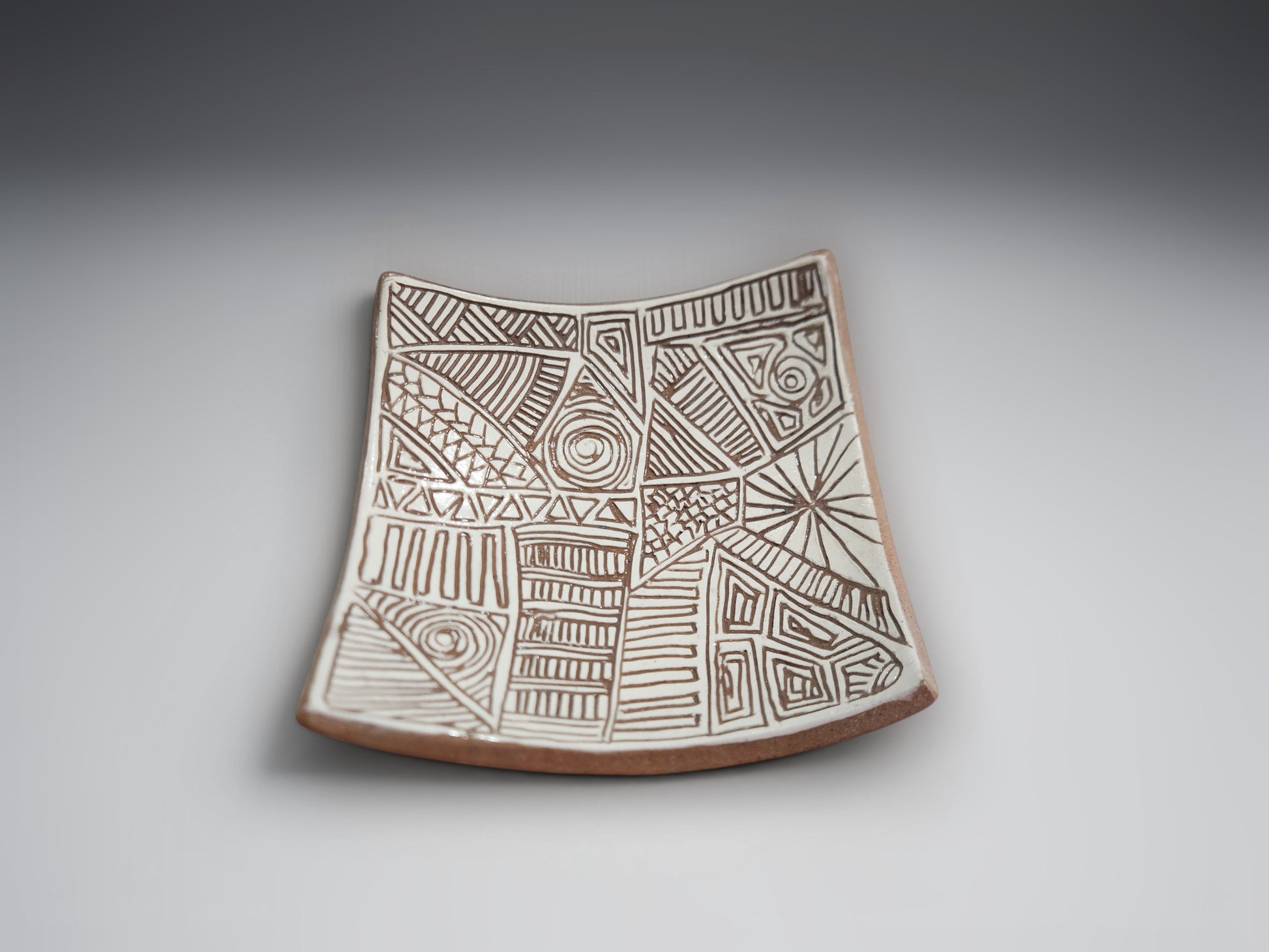 Artisan ceramic bowl-plate featuring intricate hand-carved patterns in natural terracotta clay