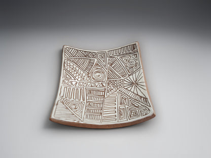 Artisan ceramic bowl-plate featuring intricate hand-carved patterns in natural terracotta clay
