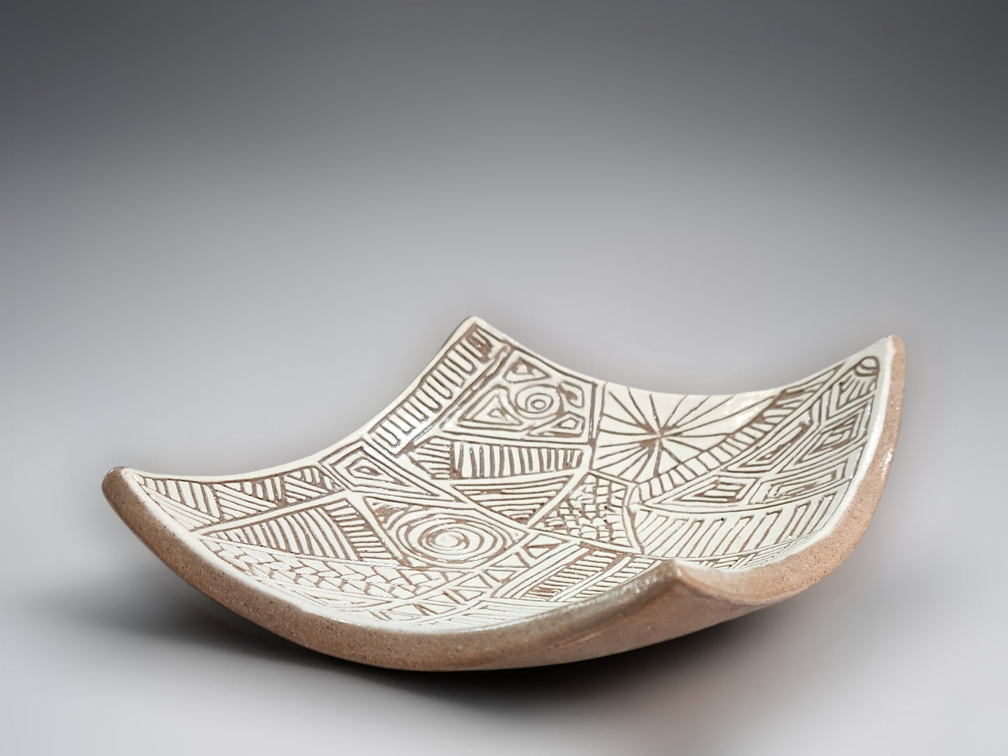 Contemporary terracotta serving dish with textured tribal-style carved interior pattern