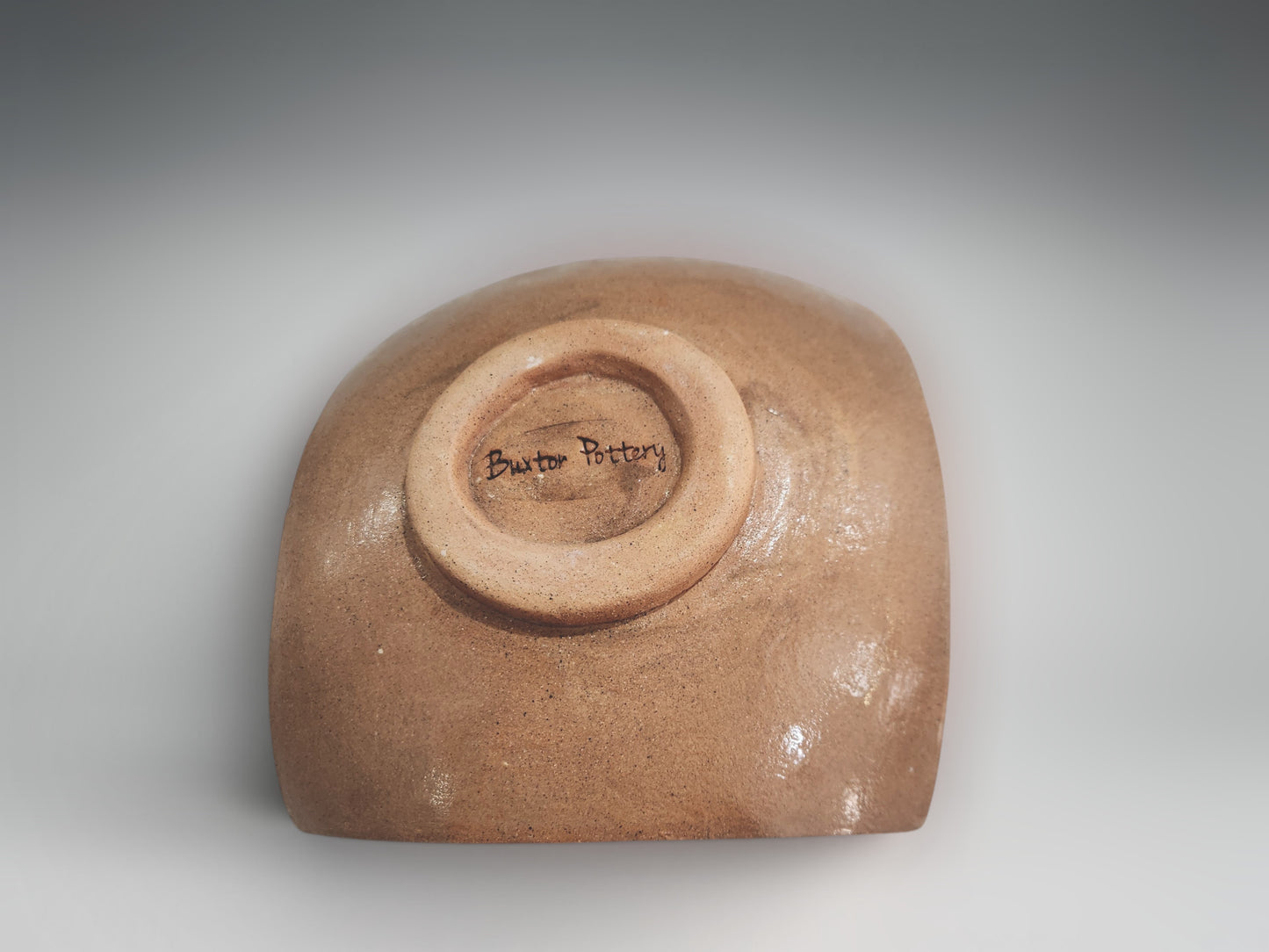 Under side of a Sculptural ceramic bowl-plate in earthy terracotta finish with intricate carved detailing