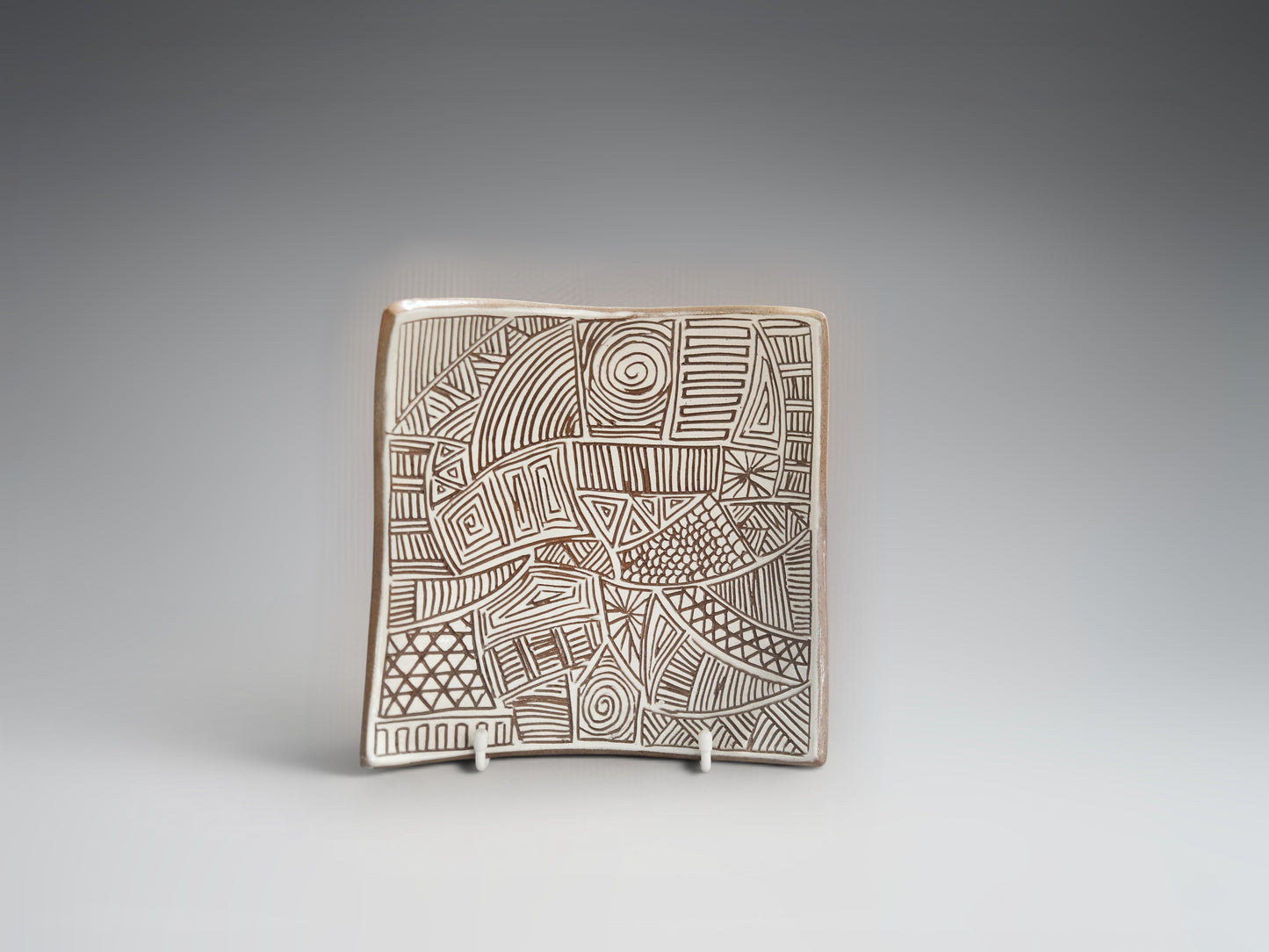 Hnad carved terracotta bowl-plate styled on a display stand.