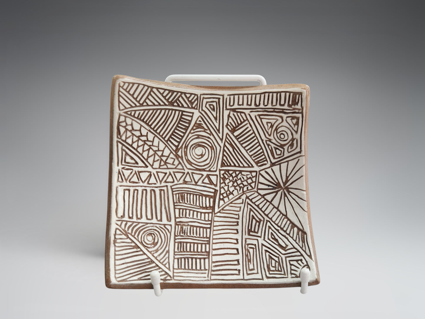 Small carved terracotta bowl-plate styled on a display stand