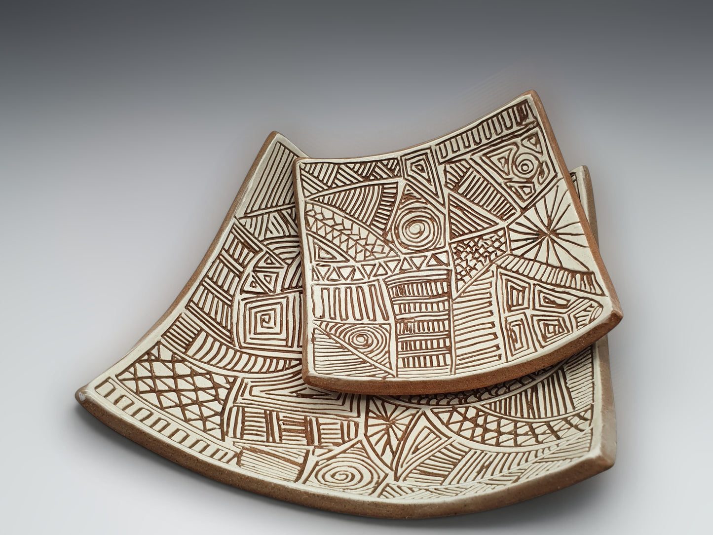 Two Handcrafted decorative terracotta dishes with carved abstract linework and natural clay tones