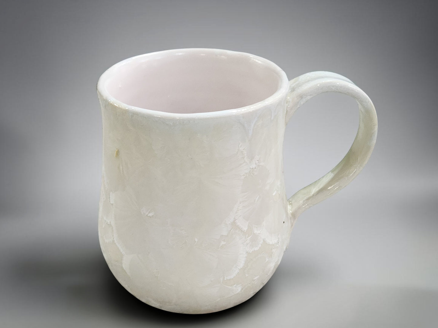 Side view of white crystalline porcelain mug with handmade handle