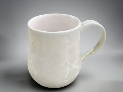 Side view of white crystalline porcelain mug with handmade handle