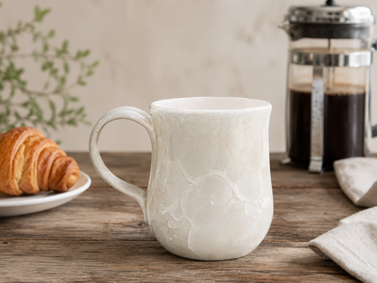 White crystalline porcelain mug with French press and croissant on a timber table