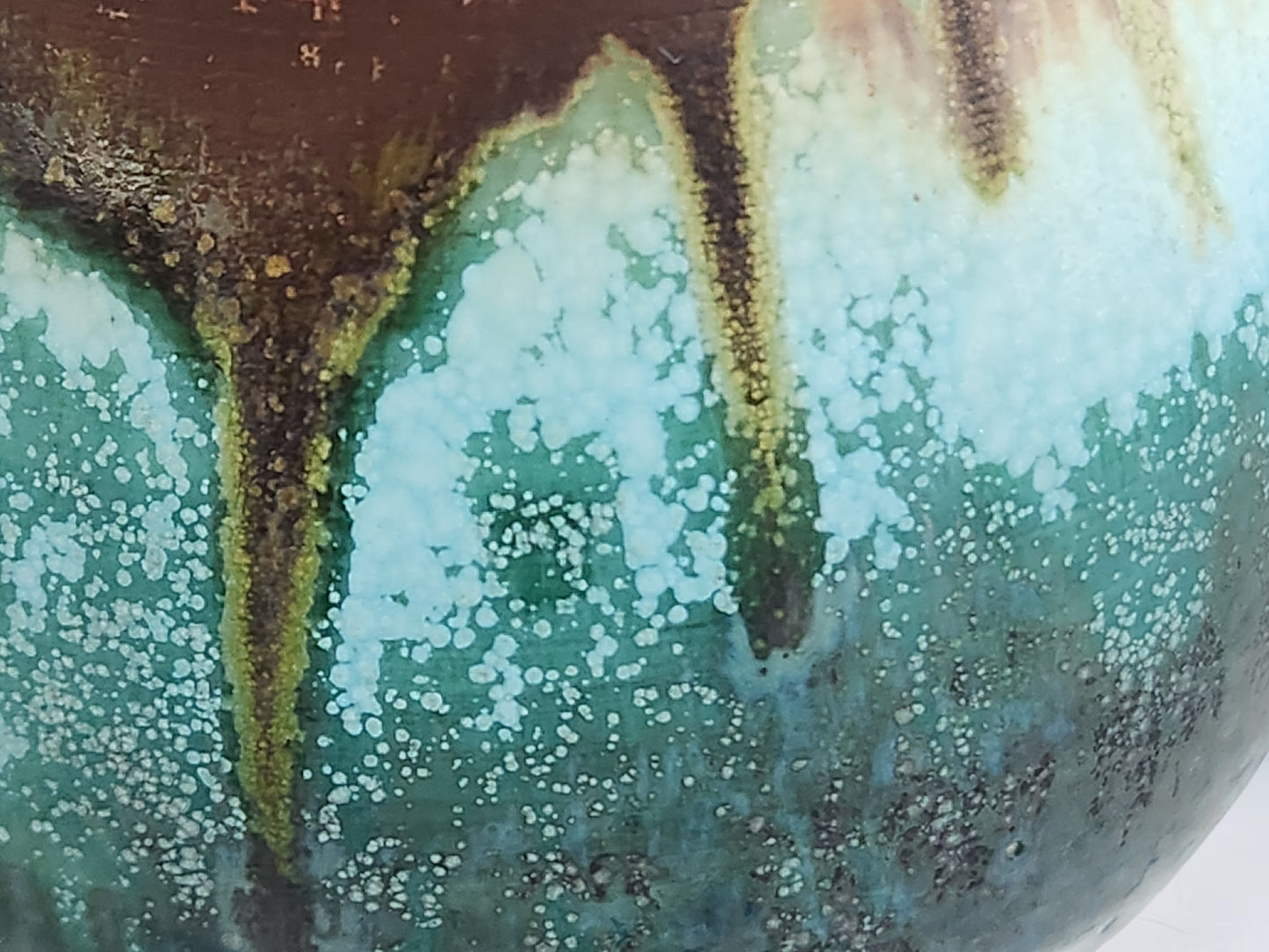 Close-up of the Bush Creek Earth glaze showing flowing turquoise, moss green and earthy brown on a handmade ceramic teacup
